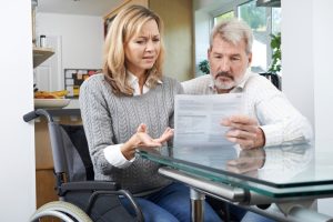 Frustrated Couple With Woman In Wheelchair Reading Disability Letter