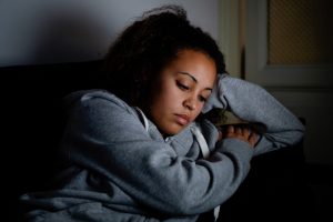 Sad woman lying on the couch at night