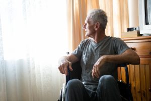 Thoughtful senior man looking away while sitting on wheelchair in nursing home